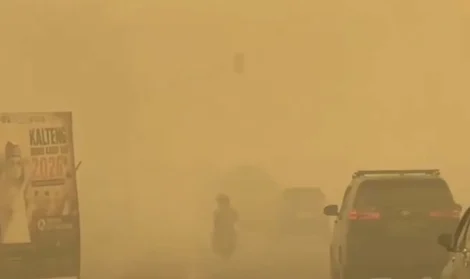 Pemandangan jalan raya tertutup kabut asap tebal berwarna kuning pekat dengan kendaraan mobil dan sepeda motor melintas di Palangkaraya