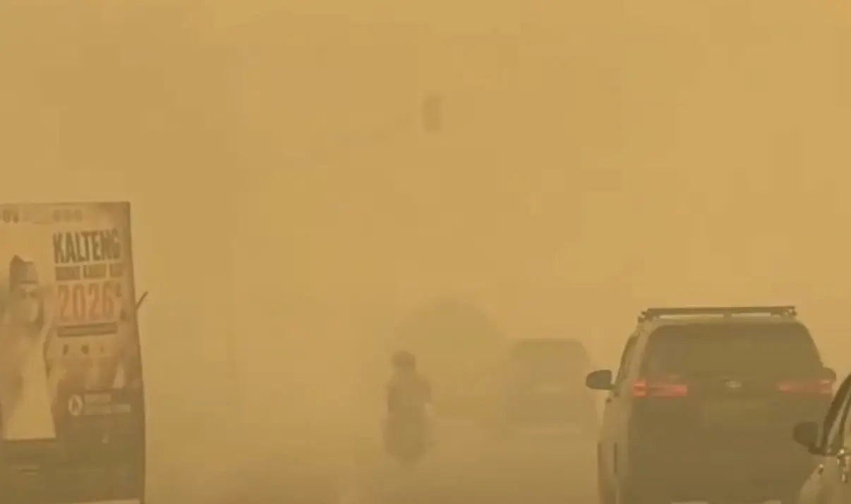 Pemandangan jalan raya tertutup kabut asap tebal berwarna kuning pekat dengan kendaraan mobil dan sepeda motor melintas di Palangkaraya